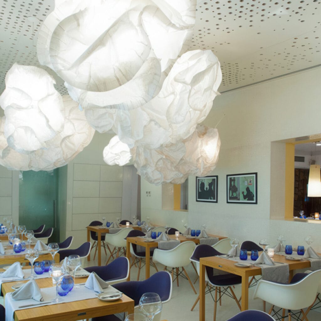 Interior elegante e contemporâneo do restaurante Pimm's Angola, com candeeiros esculturais e mesas finamente decoradas.