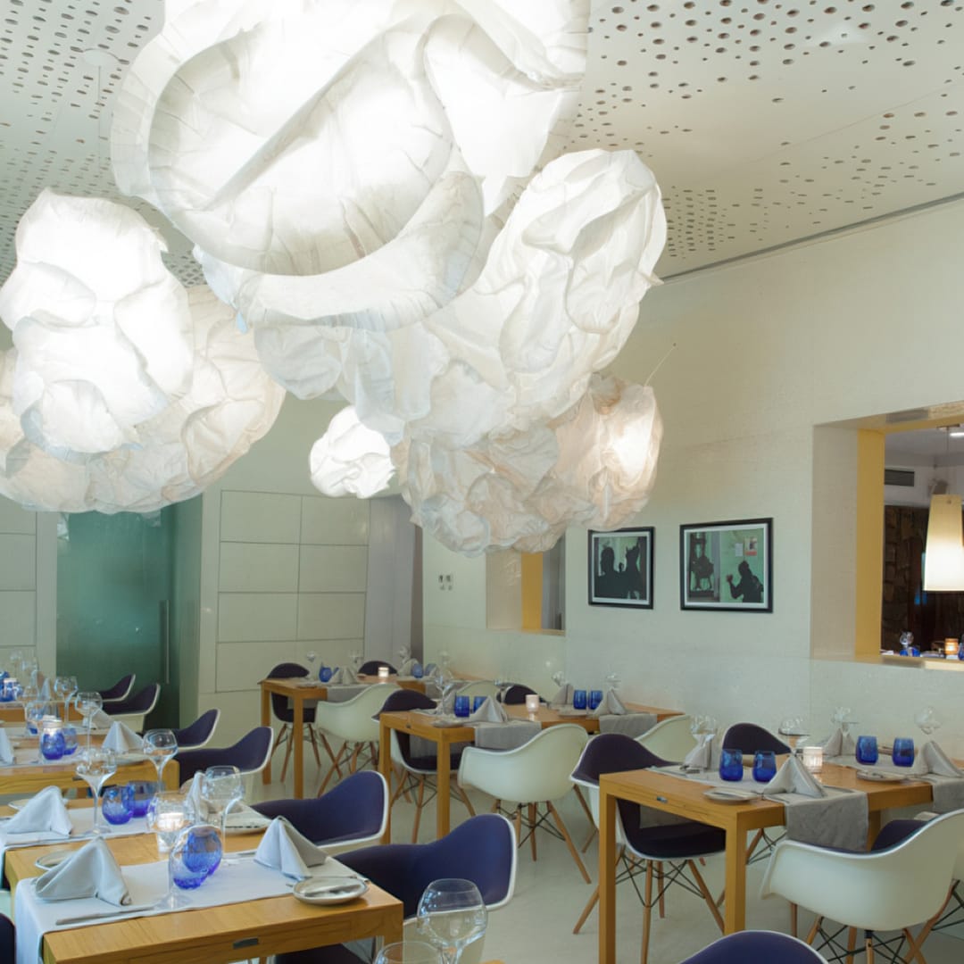 Interior elegante e contemporâneo do restaurante Pimm's Angola, com candeeiros esculturais e mesas finamente decoradas.