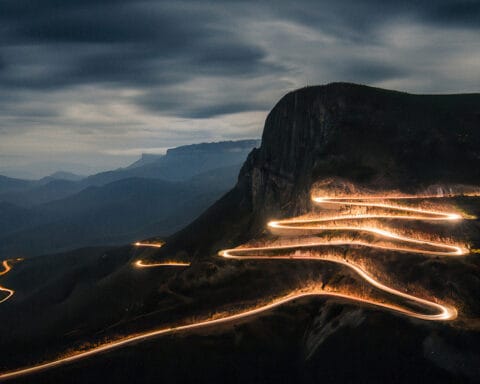 Estrada iluminada a serpentear pela montanha da Serra da Leba ao anoitecer.