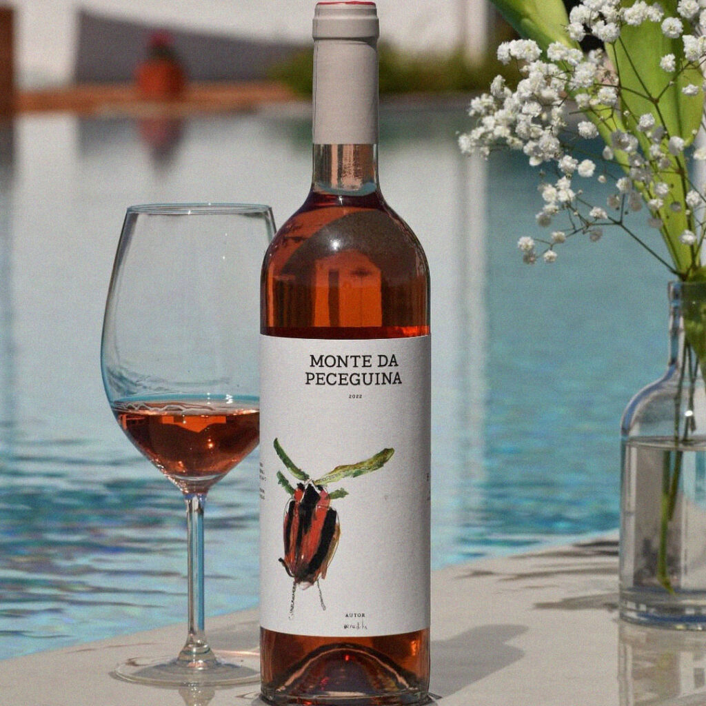 Garrafa de vinho rosé Monte da Peceguina com copo servido junto a uma piscina.