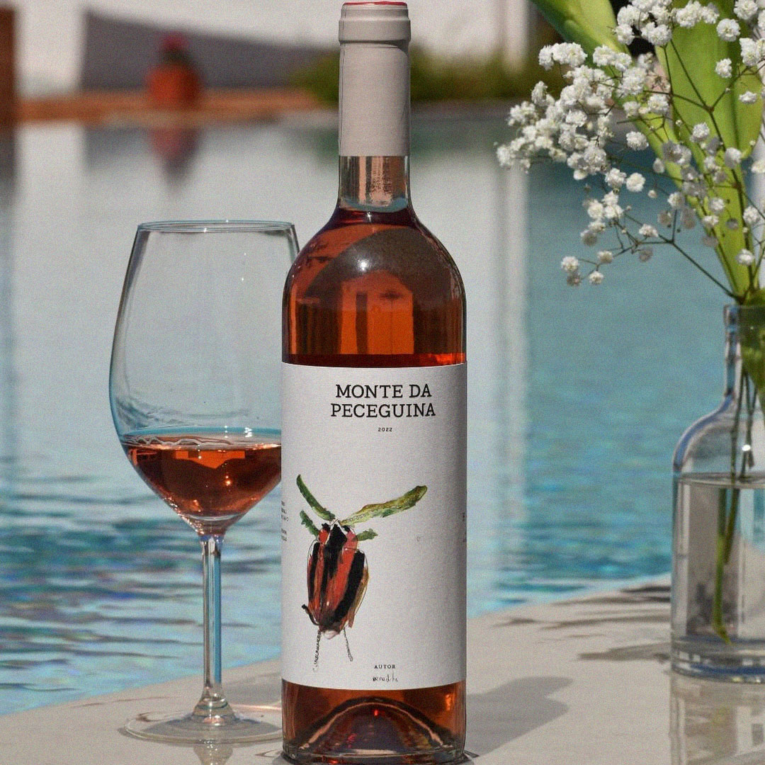 Garrafa de vinho rosé Monte da Peceguina com copo servido junto a uma piscina.
