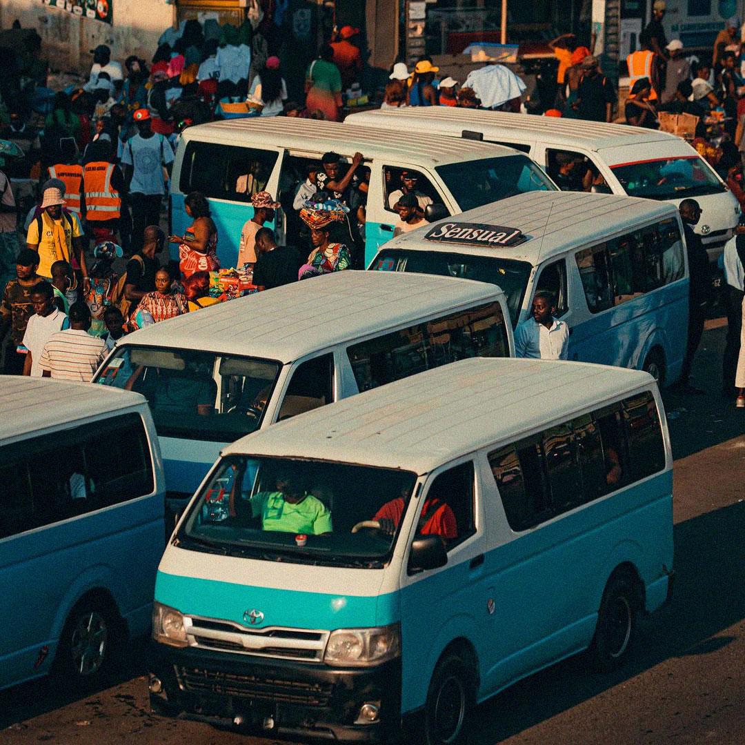 Candongueiros a circular numa rua movimentada de Luanda com passageiros.