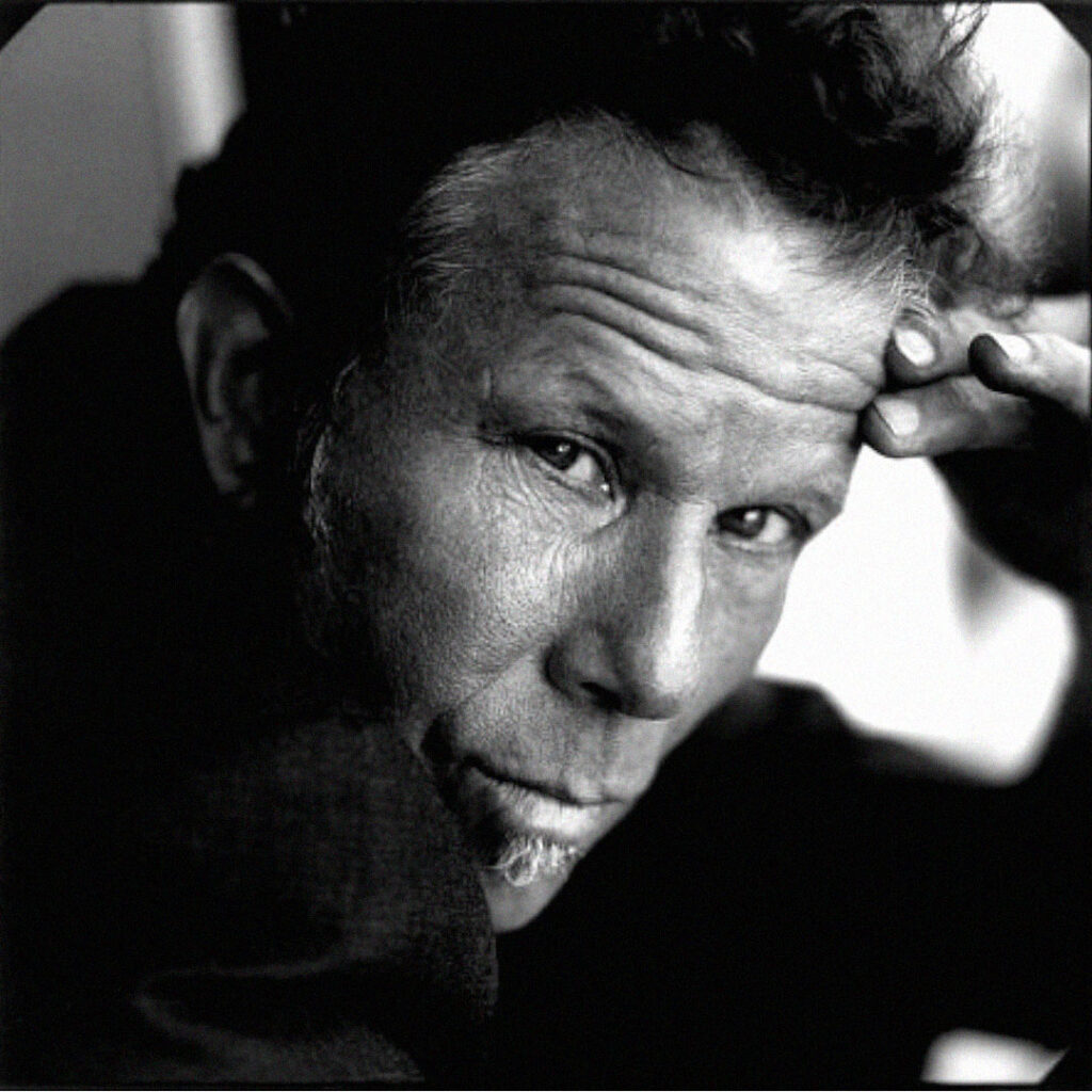 Retrato a preto e branco de Tom Waits com expressão intensa.
