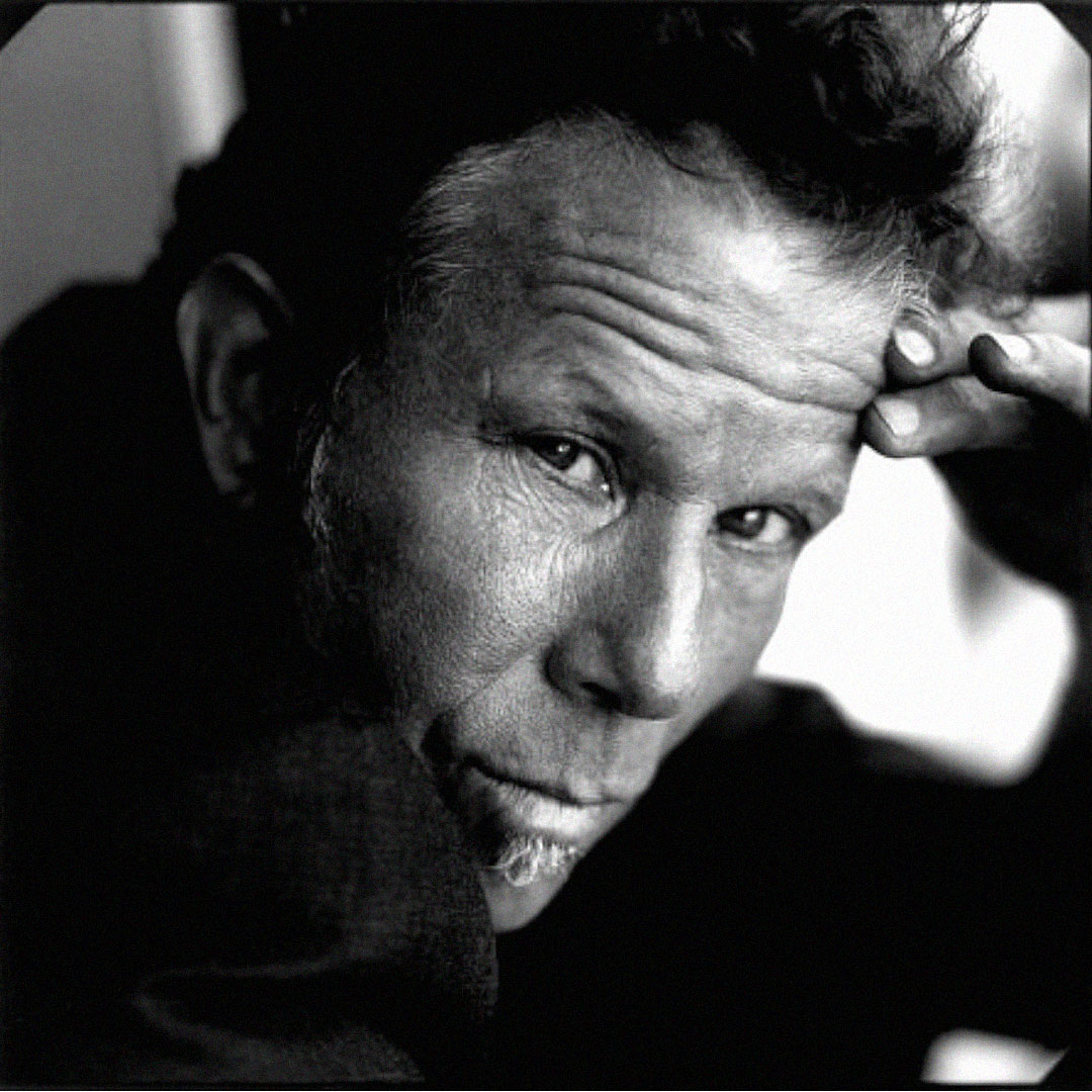 Retrato a preto e branco de Tom Waits com expressão intensa.