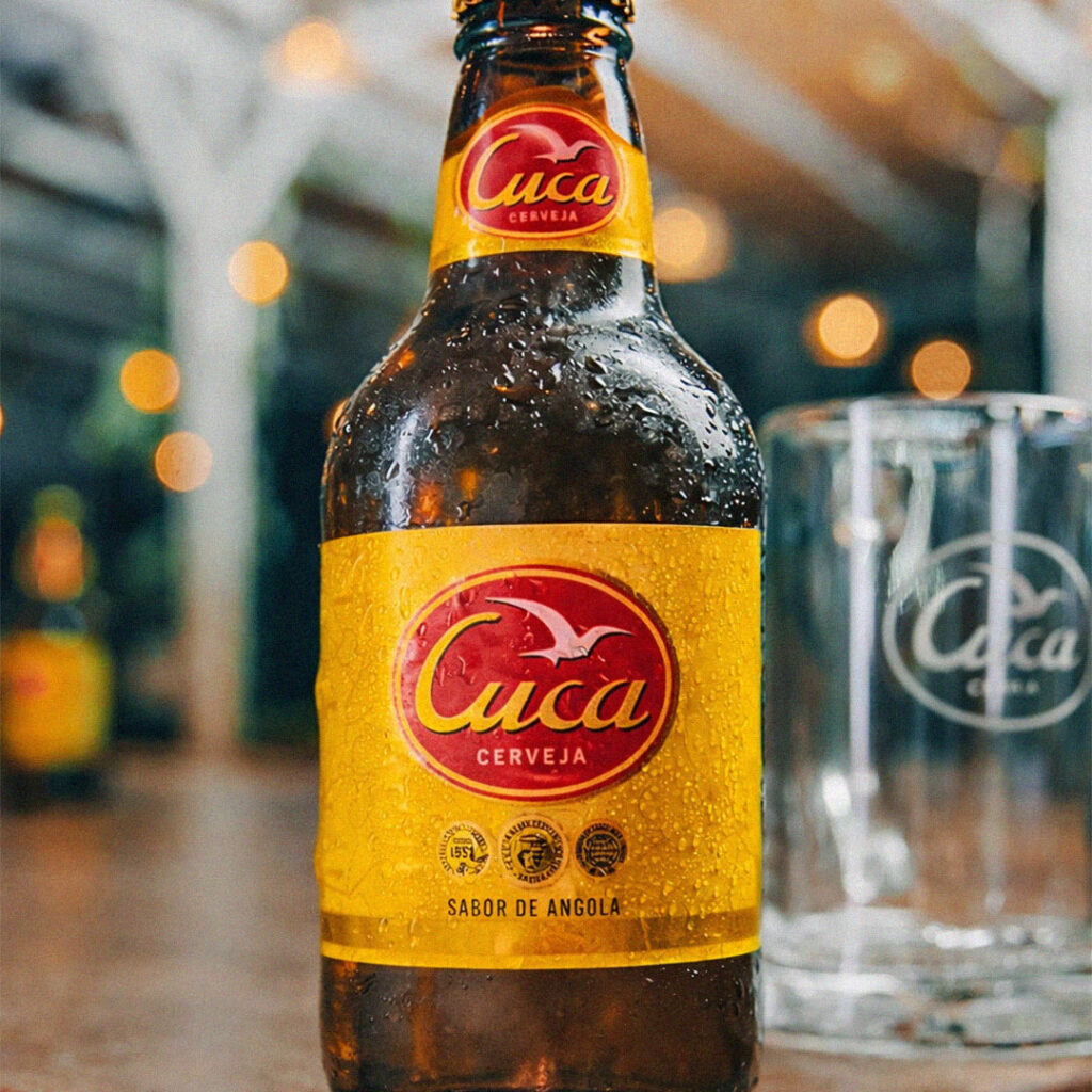 Garrafa de cerveja Cuca com rótulo visível e copo ao lado.