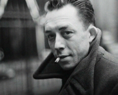Retrato a preto e branco de homem com cigarro e sobretudo.
