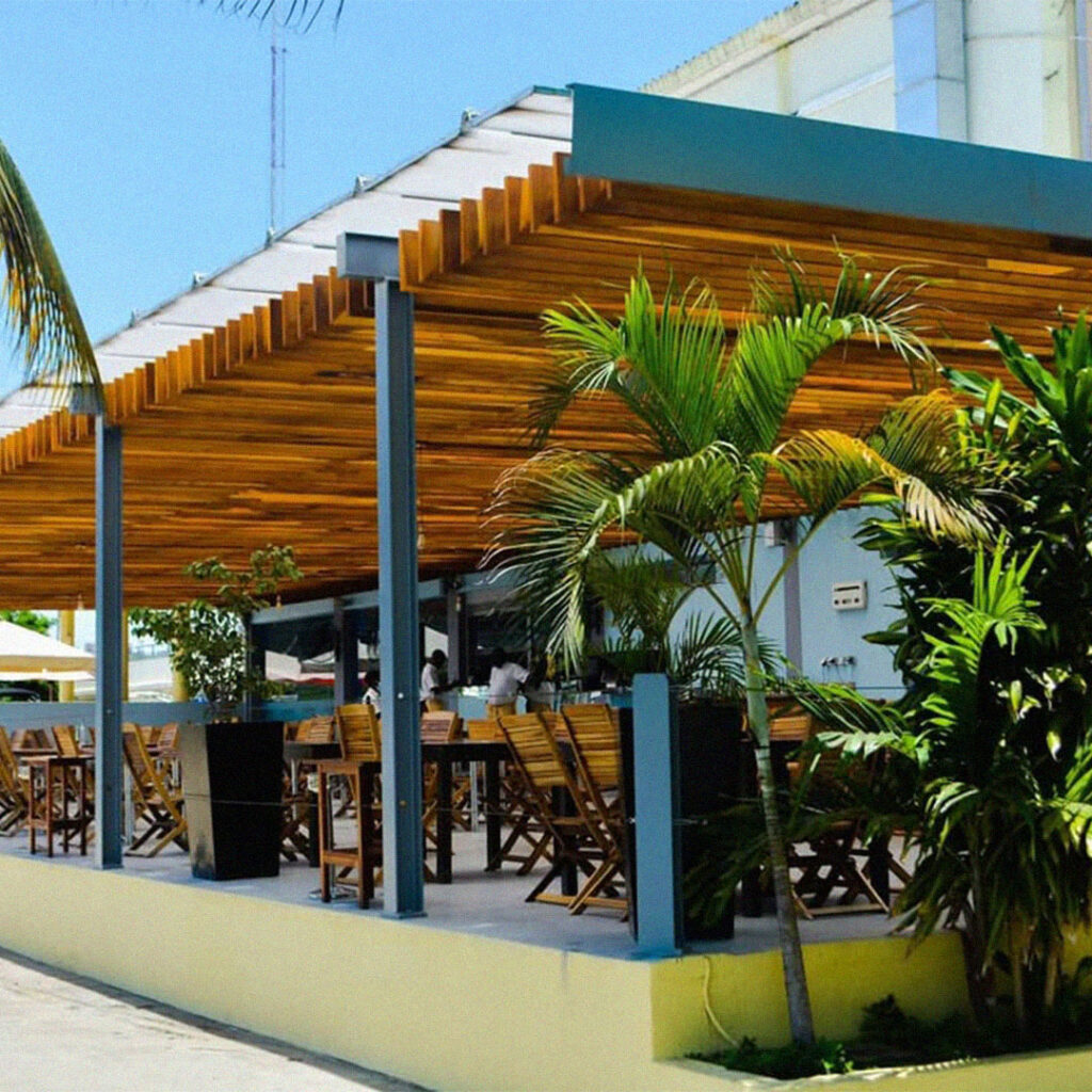 Esplanada do restaurante Convés em Luanda com cobertura de madeira, mesas ao ar livre e vegetação tropical.