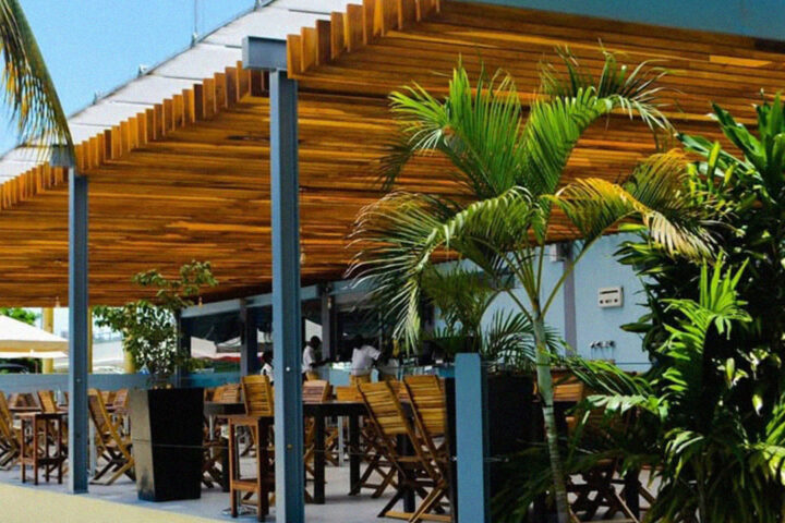 Esplanada do restaurante Convés em Luanda com cobertura de madeira, mesas ao ar livre e vegetação tropical.